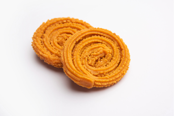 A close-up of crispy Chakli, a traditional South Indian snack made with rice flour and lentils, showcasing its spiral shape and golden-brown texture.