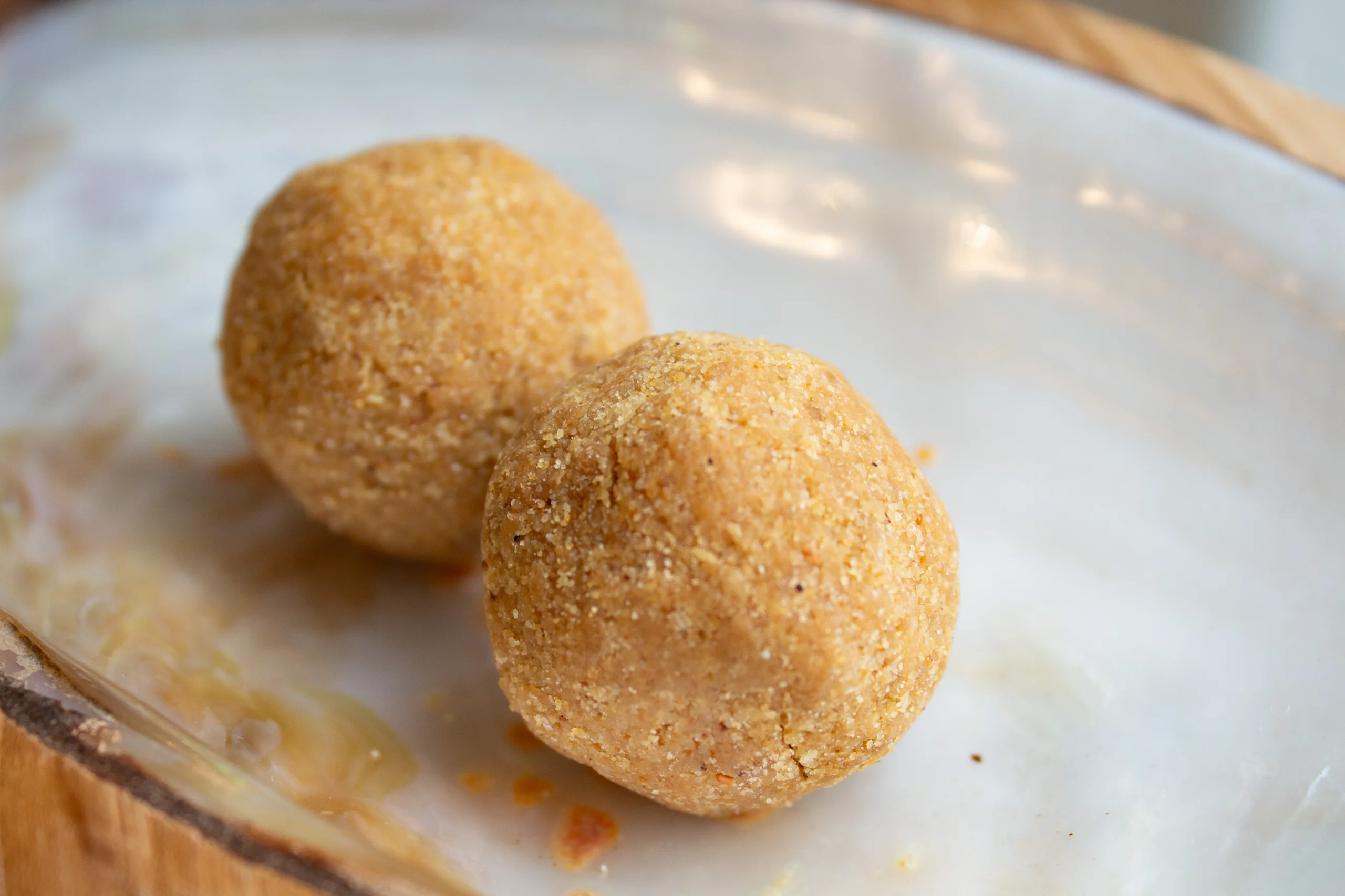 A close-up of Urad Dal Ladoo by Reddot Food, showcasing its round, textured appearance with a rich golden-brown color, highlighting the artisanal quality and traditional craftsmanship of this sweet.