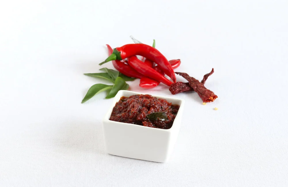 A close-up of Red Chilli Pickle from Reddot Food, featuring vibrant red chilies infused with spices, showcasing its bold and fiery appearance.