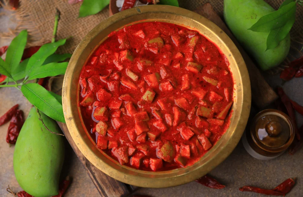 A jar of Mango Pickle from Reddot Food, featuring vibrant yellow mango chunks in a tangy and spicy sauce.