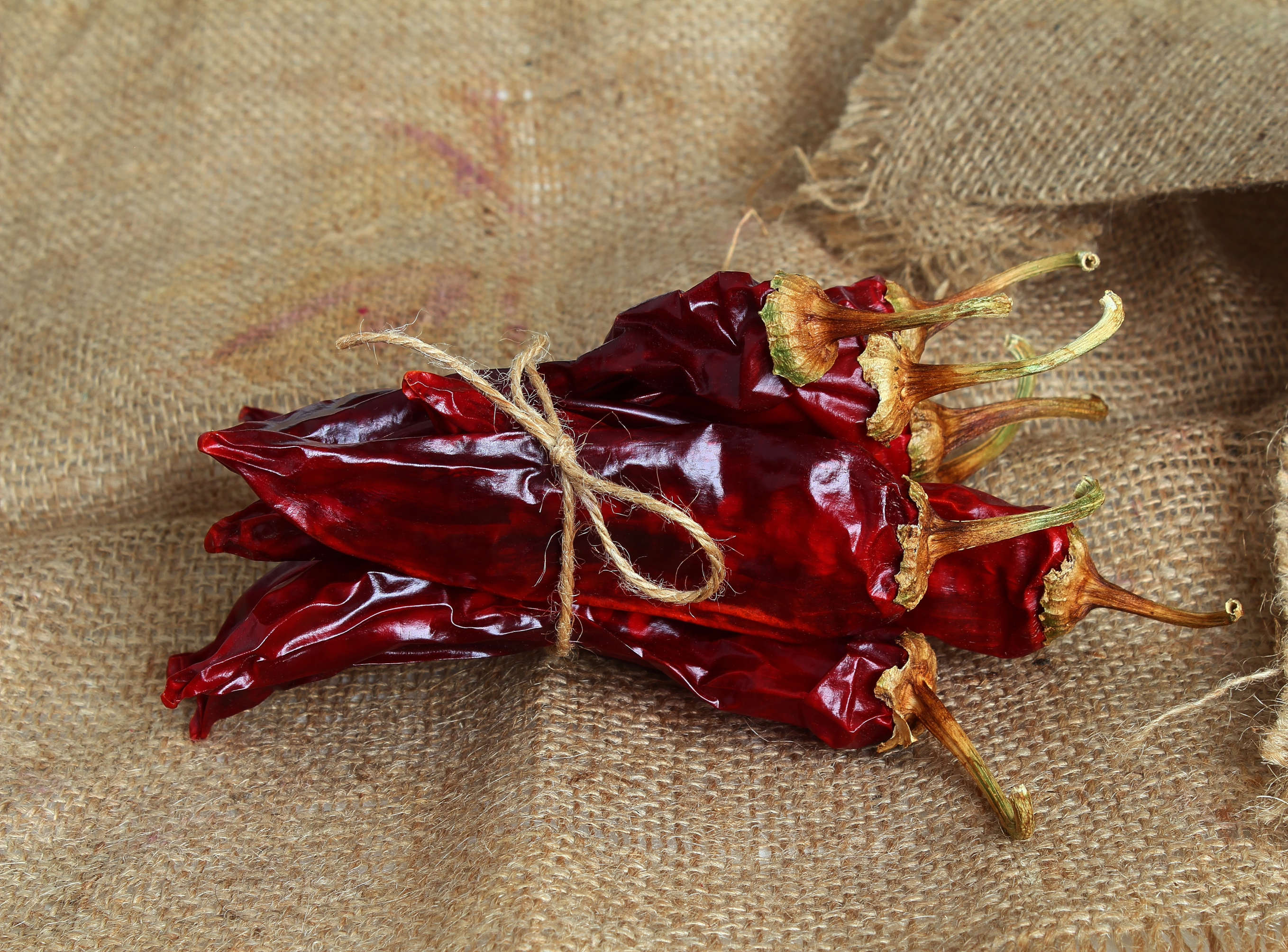 A close-up of dried red chilies, highlighting their vibrant red color and wrinkled texture.