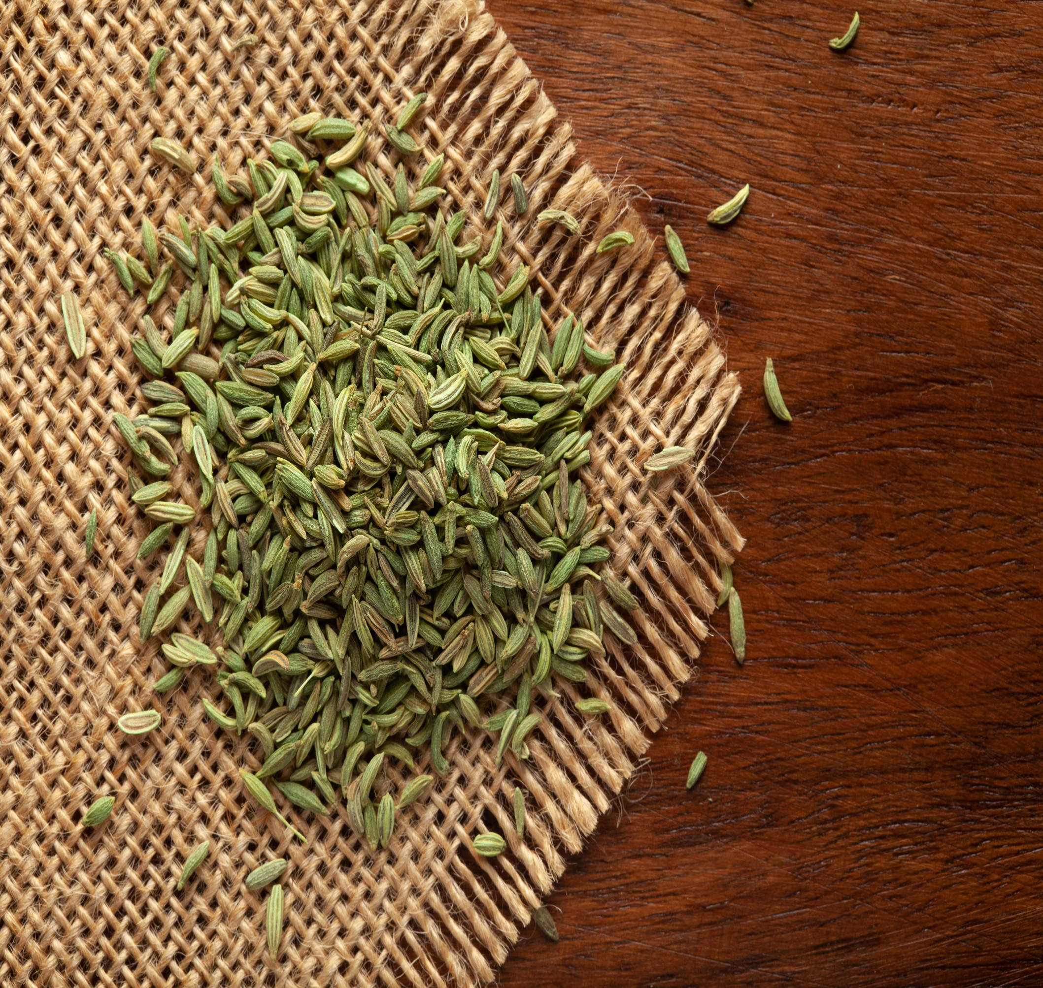 A close-up of fennel seeds, displaying their pale green color and elongated shape.